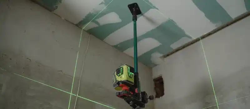 A laser level tool in action at an indoor construction site with marked walls.