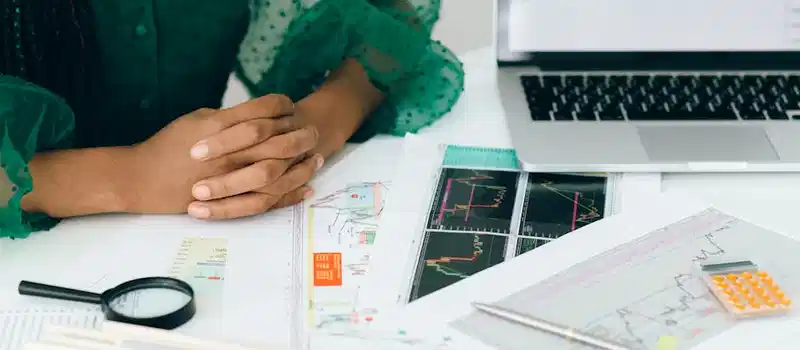 A person analyzes financial charts and graphs at a desk, indicating business trading activity.