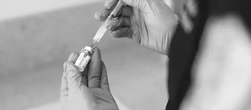 A healthcare worker prepares a syringe with medication in a clinical setting.