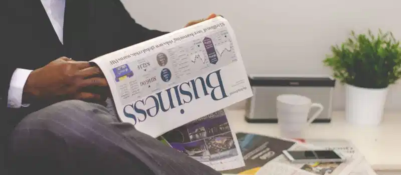 Businessman reading a financial newspaper at a desk, highlighting finance and commerce theme.