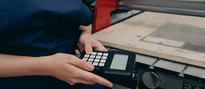 Close-up of a technician using a digital controller in an industrial setting, emphasizing technology and precision.