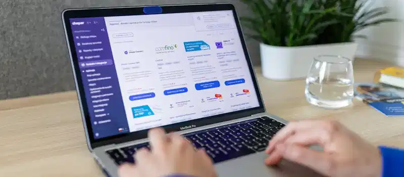 Close-up of hands on a laptop browsing an e-commerce site in a modern office.