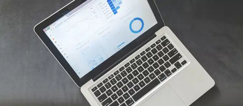 Overhead view of a laptop showing data visualizations and charts on its screen.