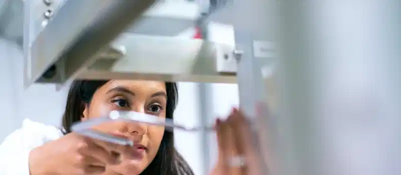 Female engineer focused on equipment in a modern lab, showcasing technology and expertise.