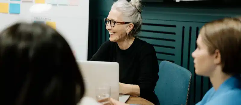 Smiling senior businesswoman leading a diverse team meeting in an office.