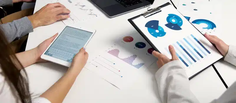 Team analyzing financial charts and digital reports during a business meeting.