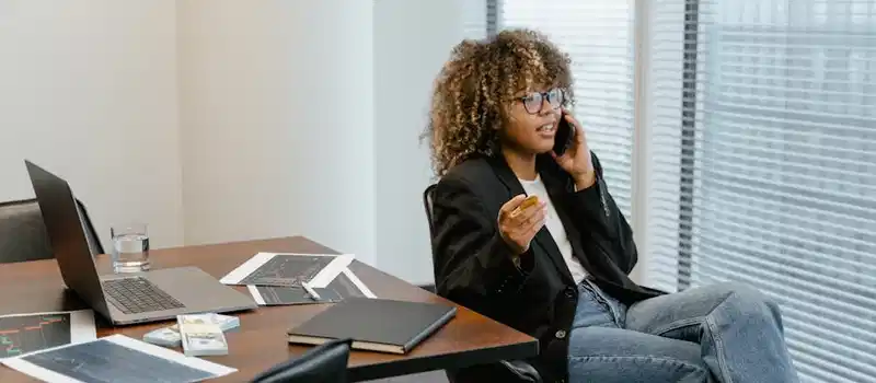 A business analyst engaged in work, sitting at a desk with a laptop and graphs.