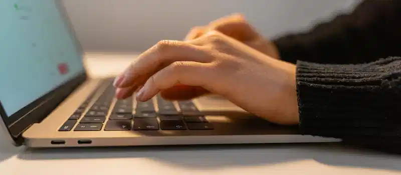 Close-up view of hands typing on a laptop keyboard, illustrating the concept of remote work and technology.