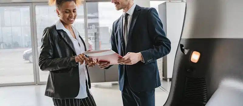 Dealer discussing vehicle options with a client inside a modern car showroom.
