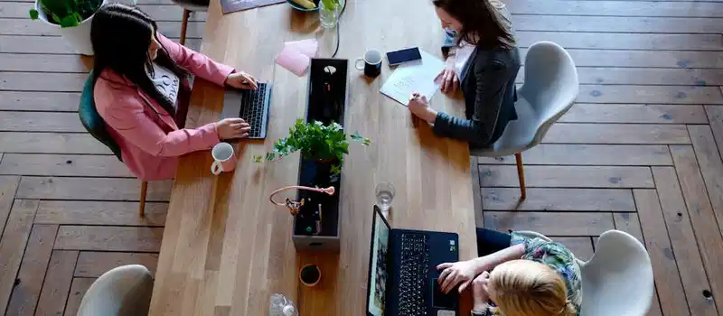 Overhead view of diverse women professionals working in a modern office setting, fostering collaboration and teamwork.