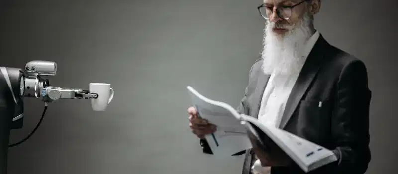 A robot arm assists a professional with a book and coffee in a modern office setup. Technology meets innovation.