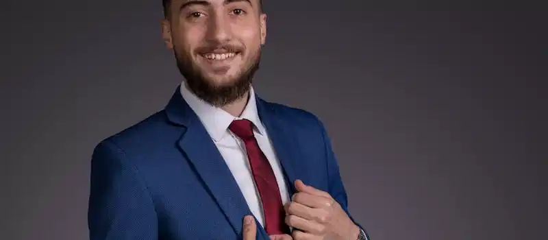 Confident young businessman in a blue suit and red tie, smiling with elegance.