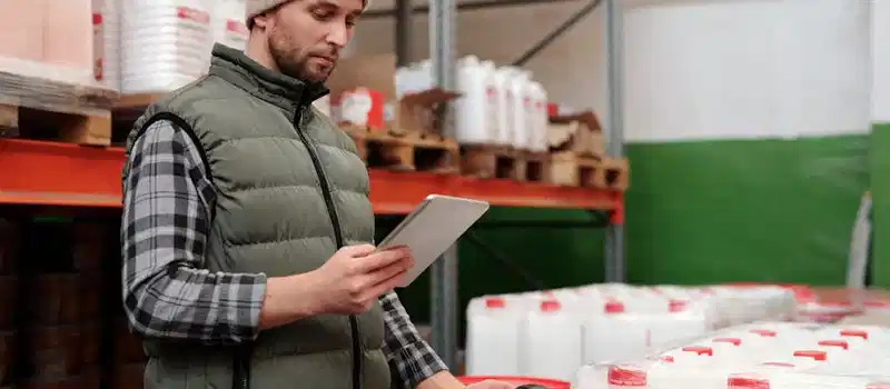 Man managing inventory with tablet in warehouse, focusing on efficiency in storage operations.
