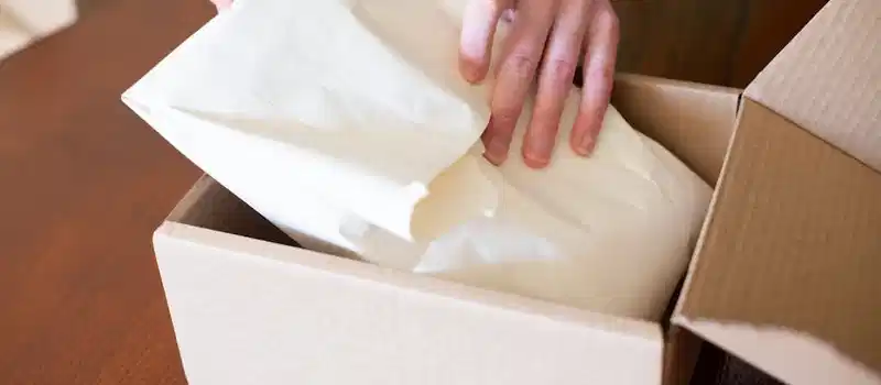 Hands wrapping merchandise in a cardboard box for shipping, ideal for small business stock images.