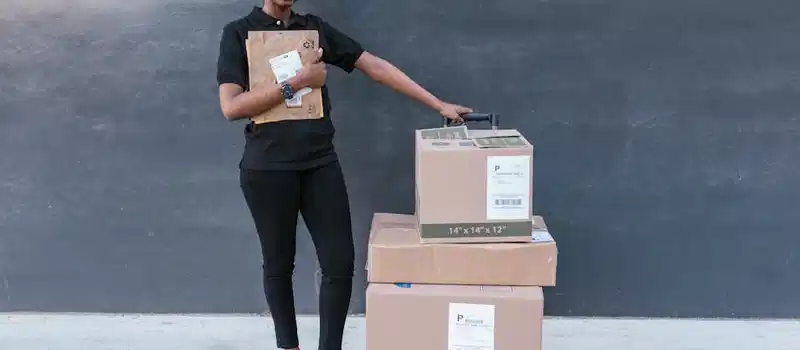 Confident woman holding delivery packages against a modern backdrop.