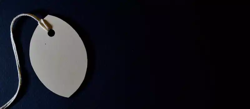 Close-up of a blank paper tag with string on a dark background, perfect for customizable designs.