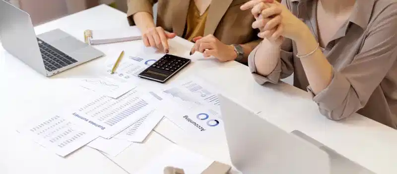 Two professionals collaborating on financial documents in a modern office setting.