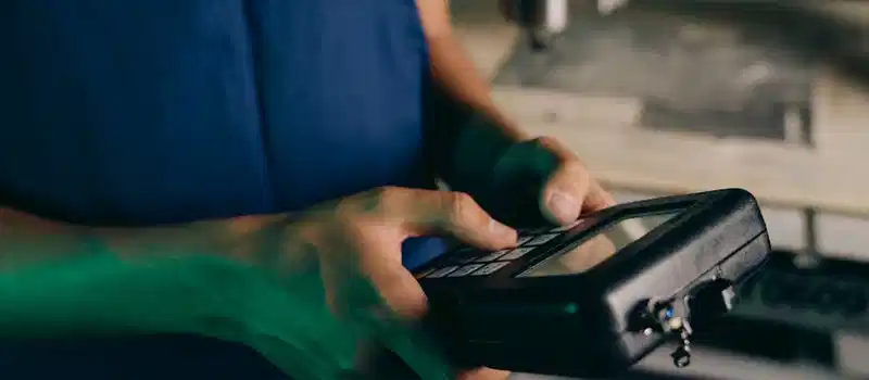 Close-up of technician using a handheld control device in a manufacturing setting.
