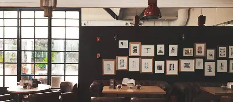 Cozy café interior featuring leather chairs, framed wall art, and pendant lighting. Ideal for meetings.