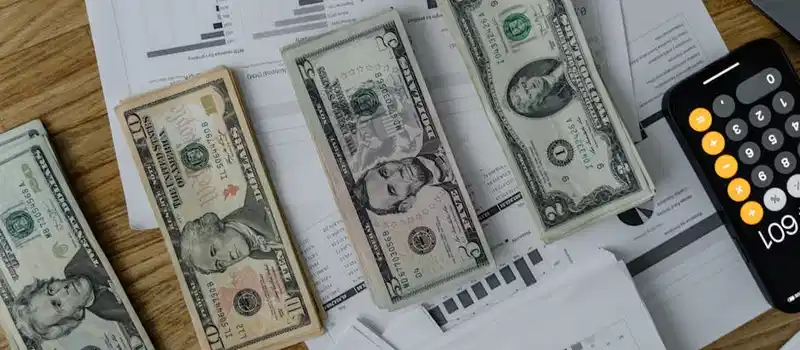 A workspace setup featuring cash, documents, and a calculator symbolizing financial analysis and budgeting.