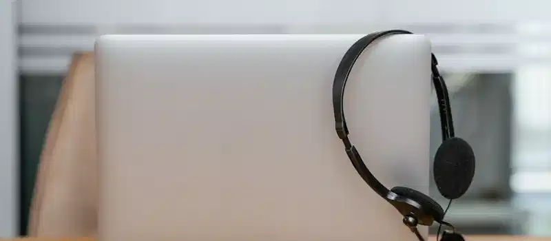 Sleek laptop and a headset on a desk, perfect for remote work or online conferences.