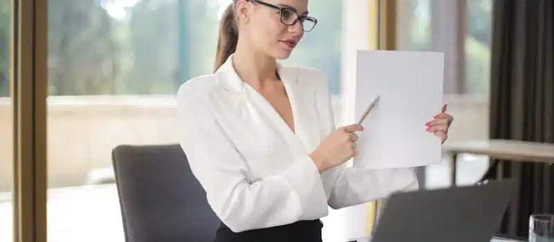 Determine female executive manager in formal wear sitting at table with laptop in office and explaining business plan