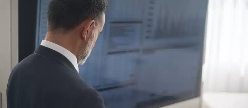 Professional analyzing stock markets on a digital tablet in a modern office setting.