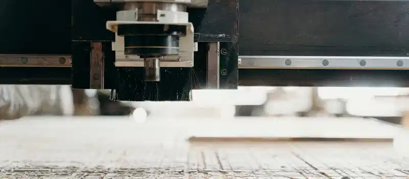 Close-up of a CNC machine carving a wooden surface indoors, showcasing precision equipment.