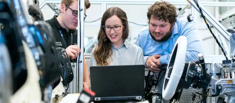 Engineers collaborating on a car project in a modern automotive workshop using advanced technology.
