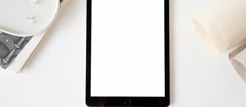 Tablet with blank screen on a minimalist white desk, ideal for mockup designs.