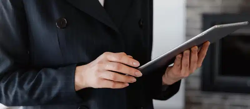 Close-up of a woman in a blazer using a digital tablet indoors.