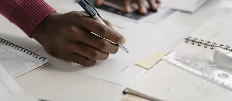 Close-up of architect drafting on blueprints in a modern office environment.