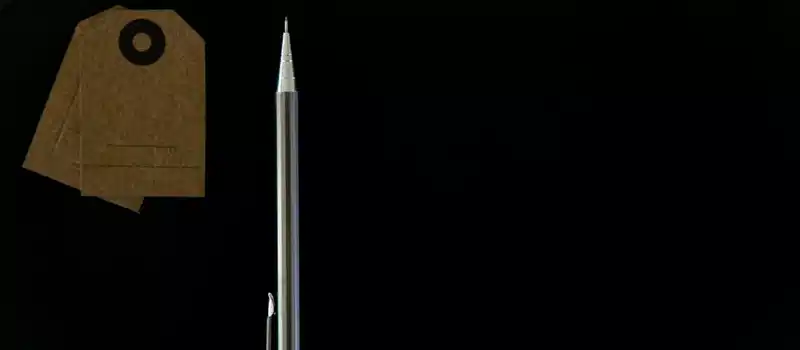 A minimalist flat lay of a metal pen and brown paper tags on a black background.