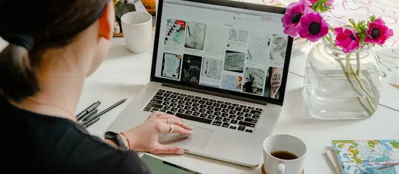 Woman in a creative workspace using a laptop and tablet for calligraphy. Artistic and tech-driven environment.