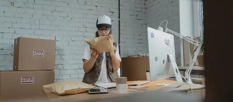 Courier in modern office checking parcel with technology and shipping materials around.