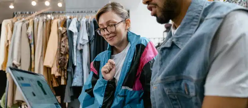 Young professionals discussing online sales strategies at a fashion store using a laptop.