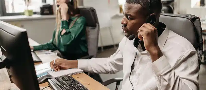 A focused team of customer service representatives working on computers and answering calls in an office