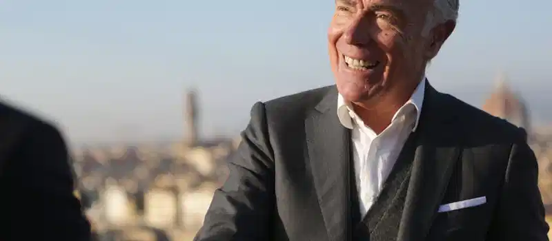 Senior businessman smiling confidently with cityscape in the background, exuding leadership and professionalism.