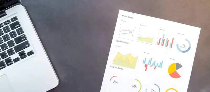 Modern desk setup with a laptop and analytical charts showcasing data interpretation and business analysis.