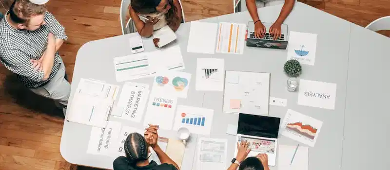 A diverse group working on marketing strategies with charts and laptops in an office setting.