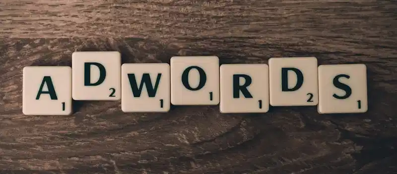 Scrabble tiles spelling 'AdWords' on a wooden surface, symbolizing digital marketing concepts.