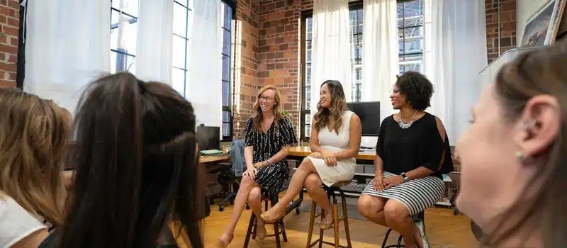 Women engaging in a panel discussion in a modern office setting, fostering an inclusive business community.