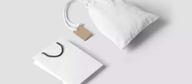 Elegant minimalist mockup featuring a white paper and cloth bag on a neutral background.