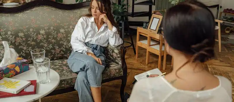 A thoughtful counseling session between a psychologist and a patient in a cozy, well-decorated room.