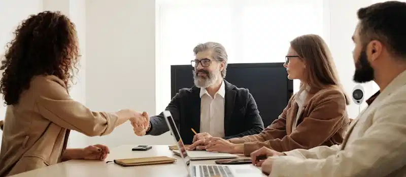 Colleagues in an office celebrating a successful negotiation with a handshake.