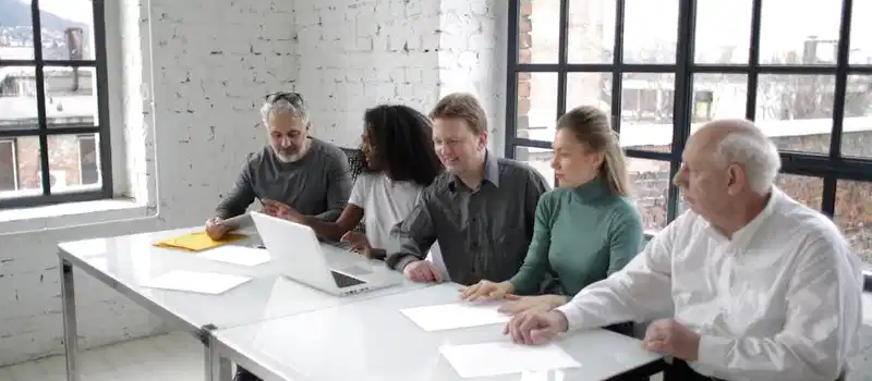 A group of professionals discussing ideas around a table in a bright, modern office setting.