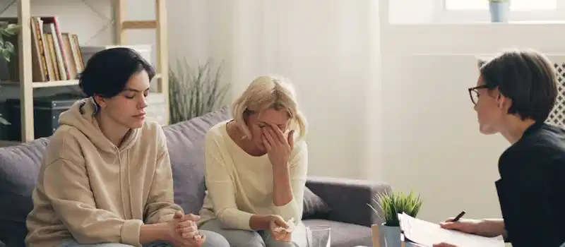 Emotional family therapy session with a therapist indoors, conveying connection and support.