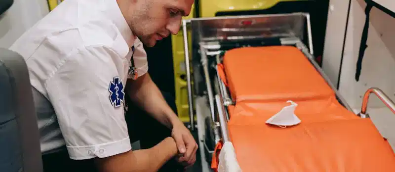 A paramedic prepares a stretcher inside an ambulance, focusing on readiness and professionalism.