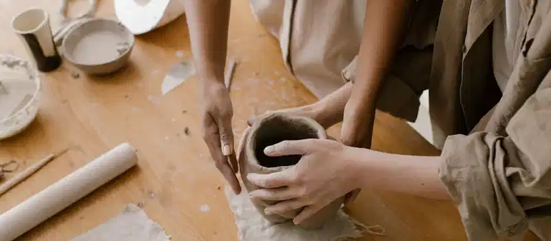 Close-up of hands crafting a pottery vase in an art studio setting.