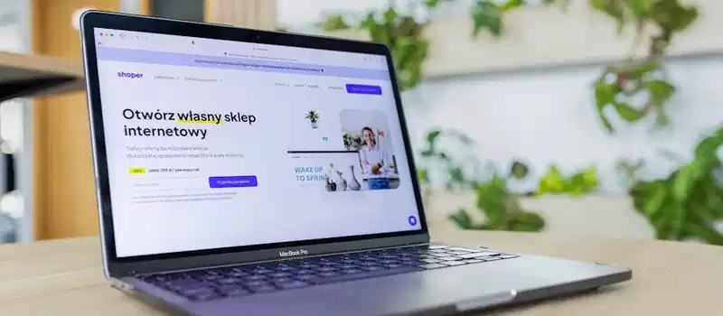 Close-up of a laptop with an open e-commerce website, surrounded by modern office decor.